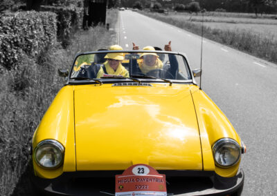 Gele MG B Tourer met twee dames compleet gehuld in gele kleding en accessoires.